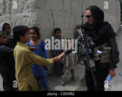 Un esercito usa un sostegno culturale membro della squadra di Operazioni Speciali scuote la mano di un giovane mentre afghano di pattuglia 24 maggio 2012 nel distretto di Kunar, Afghanistan. Lo scopo della sorveglianza è stata per ottenere atmospherics dagli abitanti locali e per il CST per interagire con le donne afghane. Foto Stock