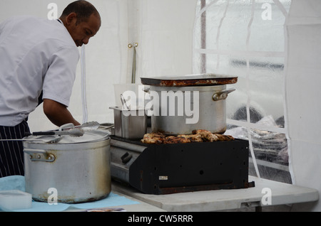 Lo chef prepara cibi Afro-caraibici su un mercato in stallo Foto Stock