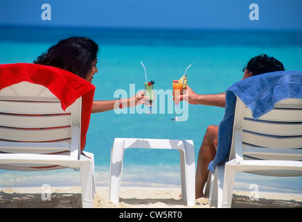 Giovane tostare un'isola incantevole vacanza con bicchieri riempiti con colorati drink tropicali Foto Stock