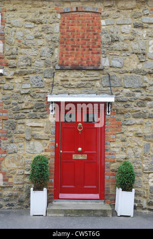 Dipinto di rosso porta di legno in mattoni e muro di pietra di casa a Petworth. West Sussex. Inghilterra Foto Stock