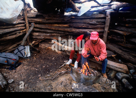 Coppia con grezzo fuoco improvvisati in baita in legno sotto il monte Fitzroy a Los ghiacciai Parco Nazionale in Patagonia, Argentina Foto Stock