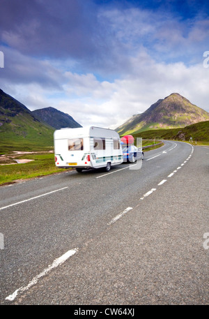 Una vettura di un sistema di traino caravan lungo la A82 attraverso Glencoe nelle Highlands della Scozia Foto Stock