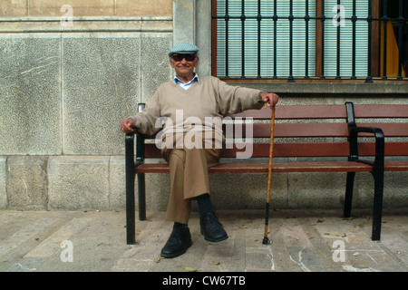 Il vecchio uomo con cappello, occhiali da sole e bastone, seduta su una panchina di fronte a casa sua, Spagna, Balearen, Maiorca, Alcudia Foto Stock