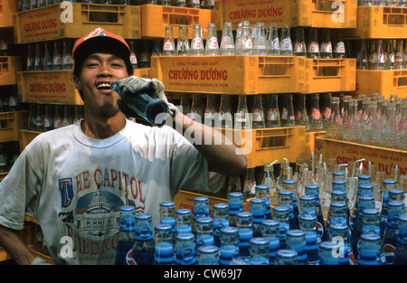 Giovane uomo tra le bottiglie di vetro, Vietnam Foto Stock