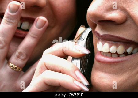 Sorridente due giovani donne, una parlando al cellulare Foto Stock