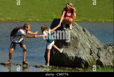 Famiglia attraversando un lago nelle Alpi francesi, Francia, Alpi Foto Stock