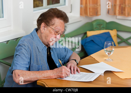 Vecchia donna a firmare un contratto Foto Stock