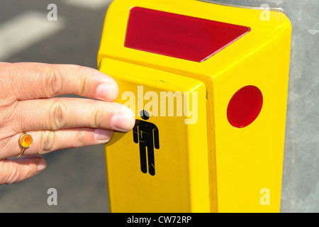 Close-up di una mano premendo il pulsante della luce di pedone con segnale acustico per i non vedenti Foto Stock