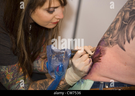 Femmina tatooing tattooer un uomo con la schiena, Germania Foto Stock