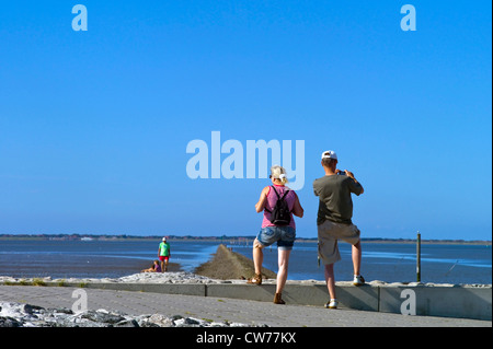 I turisti in piedi sulla mole, Germania, Bassa Sassonia, Neuharlingersiel Foto Stock