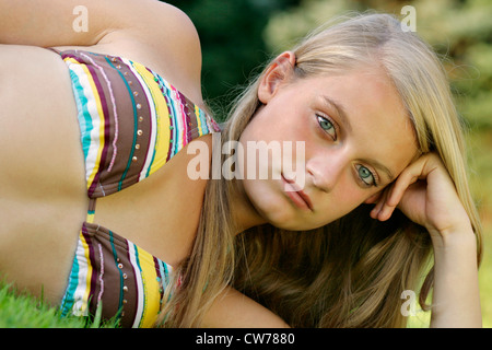 Giovane ragazza in bikini, sdraiato su un prato Foto Stock