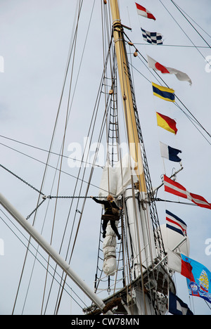 Marinaio femmina di arrampicata in piattaforme di Tall Ship Foto Stock