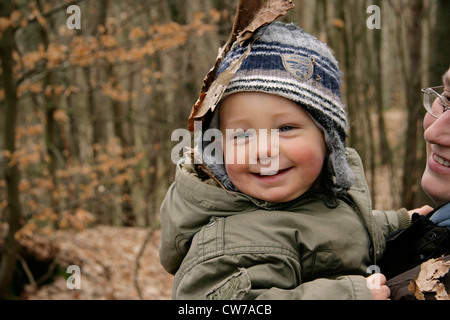 Little Boy holding sulla madre di braccia in autunno la foresta, Germania Foto Stock