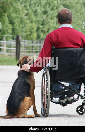 Uomo in una sedia a rotelle con il cane Foto Stock