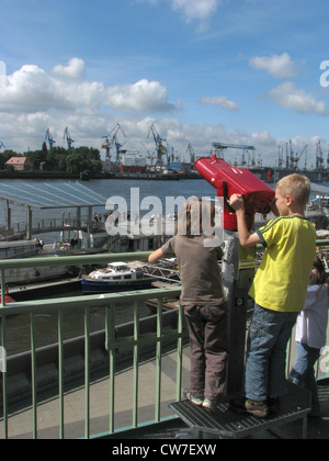 I bambini stanno a guardare attraverso un paio di binocoli su per le banchine al Landungsbruecken nel porto di Amburgo, Germania, Amburgo Foto Stock