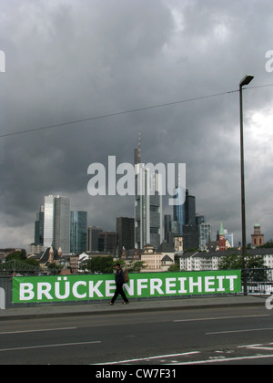 Nuvoloso vista dello skyline di Francoforte da un ponte sul fiume principale - lettura del segno "Brueckenfreiheit' ('Ponte della Libertà"), Germania, Francoforte Foto Stock