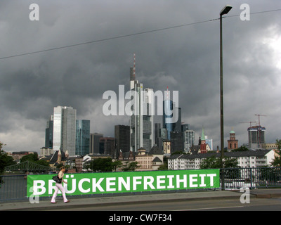 Nuvoloso vista dello skyline di Francoforte da un ponte sul fiume principale - lettura del segno "Brueckenfreiheit' ('Ponte della Libertà"), Germania, Francoforte Foto Stock