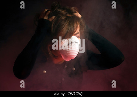 Donna in maschera medica all'interno di nuvole di fumo Foto Stock