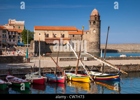 Barche colorate e nuotatori in vacanza sotto Eglise Notre Dame des Anges Chiesa, Collioure, Languedoc-Roussillon, Francia Foto Stock