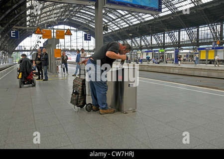 Uomo di raccolta bottiglia restituibili da un bidone dei rifiuti sulla stazione principale di Colonia, in Germania, in Renania settentrionale-Vestfalia, Colonia Foto Stock