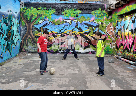 Serbo, tedesco e Thai boys insieme giocando a calcio per strada, in Germania, in Renania settentrionale-Vestfalia, Colonia Foto Stock