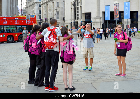 Team London Ambassadors in uniforme ufficiale in posa per foto con turisti canadesi Giochi Olimpici di Londra 2012 a Trafalgar Square Londra Inghilterra Regno Unito Foto Stock