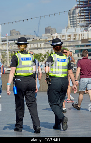 Vista posteriore di due poliziotti metropolitane del WPC in uniforme in pattuglia a piedi sul Tamigi presso Butlers Wharf Southwark Londra Inghilterra Regno Unito Foto Stock