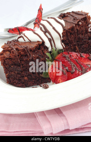 Brownie al cioccolato con panna e fragole. Su uno sfondo di colore rosa. Foto Stock