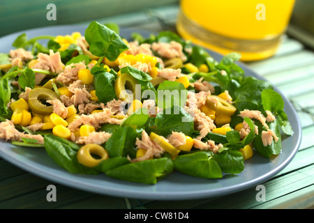 Tonno fresco, granturco dolce, verde oliva e insalata di crescione con succo di arancia in retro Foto Stock