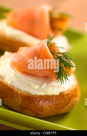 Salmone affumicato e crema di formaggio crostini guarnito con aneto (messa a fuoco selettiva, messa a fuoco sulla parte anteriore del salmone) Foto Stock