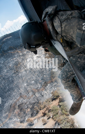 Sgt. Chris Boni, California esercito Guardia nazionale capo equipaggio da 1-140esimo battaglione aviazione (Air Assault) fuori Los Alamitos formazione congiunta di base (JFTB), rilascia l'acqua da sopra la testa mentre si combatte il fuoco di RIM in Kern County. La UH-60 equipaggio irrorato il cerchione al fuoco con un totale di 30,111 galloni passato tre giorni mentre combattendo il complesso di Jawbone di incendi a sostegno del Bureau of Land Management, Kern County fire e CAL FIRE. Foto Stock