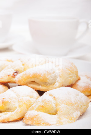 Primo piano della marmellata fatta in casa riempiti crescent rotoli bianco e tazze di tè Foto Stock