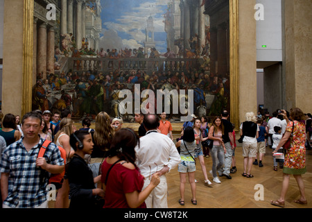 I turisti si mescolano al di sotto delle nozze di Cana (o le nozze di Cana), un enorme dipinto dal tardo-rinascimentale manierista o pittore italiano, Paolo Veronese - sul display al Musée du Louvre di Parigi, dove si trova la più grande pittura museo della collezione. Foto Stock