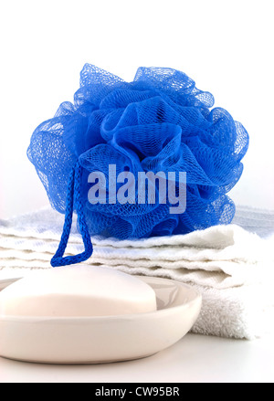 Bagno blu pasta o una spugna con pulire asciugamano bianco e sapone nel piatto su sfondo bianco. Foto Stock