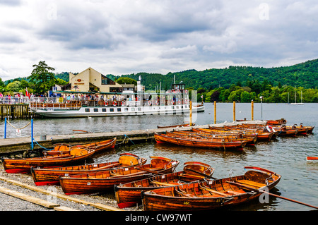 Svuotare le barche a remi redatto sulla spiaggia di ciottoli come escursionisti a bordo del vaporetto storico (ora diesel), MV Tern, Lago di Windermere Foto Stock