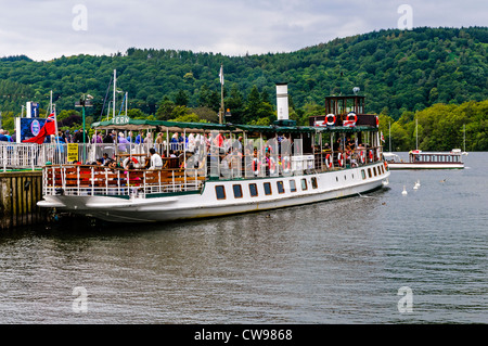 I passeggeri a bordo del vaporetto storico (ora il diesel) MV Terna per un viaggio attorno al lago di Windermere, bordati da densamente boscose colline Foto Stock