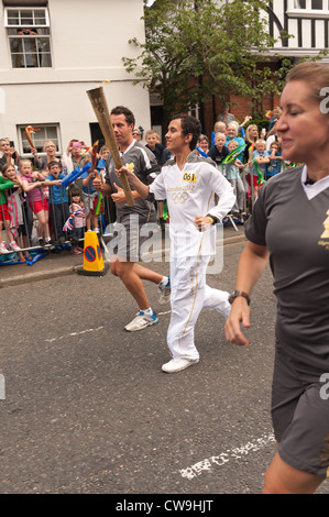 Giochi olimpici toccare portatore e relè associati competenti in una processione ad elevata tenuta di strada con la folla in attesa Foto Stock