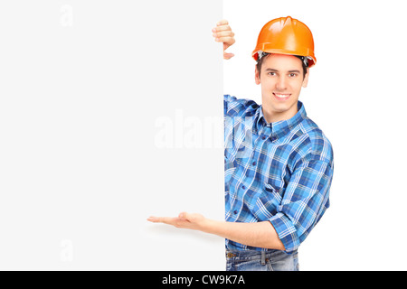 Un lavoratore edile con casco in posa dietro un pannello vuoto isolato su bianco Foto Stock