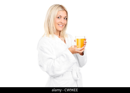 Una giovane donna in accappatoio bere il succo d'arancia a colazione isolati su sfondo bianco Foto Stock