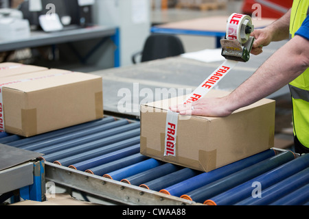 Uomo di imballaggio scatola di cartone in magazzino Foto Stock