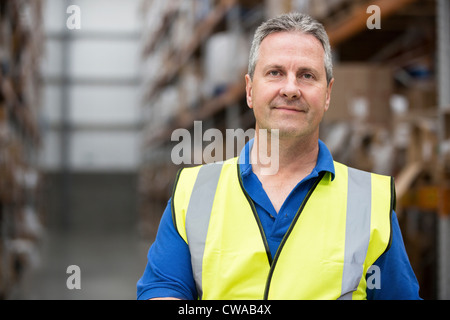 Uomo di indossare indumenti ad elevata visibilità in magazzino, ritratto Foto Stock