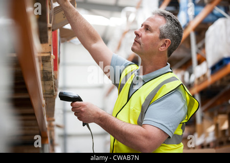 L'uomo utilizzando il lettore di codici a barre nel magazzino Foto Stock