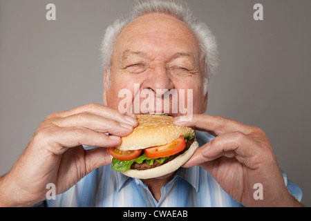 Senior uomo mangiare hamburger Foto Stock