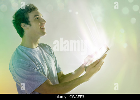 Giovane uomo guardando alla luce proveniente tavoletta digitale Foto Stock