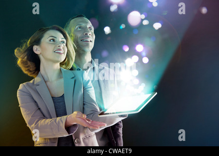 Gli imprenditori guardando le luci provenienti dalla tavoletta digitale Foto Stock