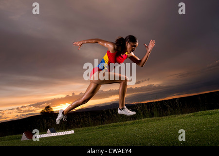 Atleta femminile si spostano fuori dai blocchi di partenza Foto Stock