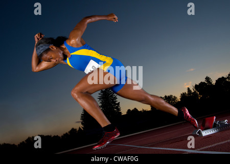 Atleta femminile di lasciare i blocchi di partenza Foto Stock