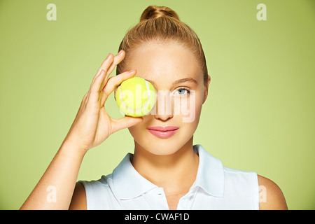 Giovane donna tenendo palla da tennis oltre il suo occhio Foto Stock