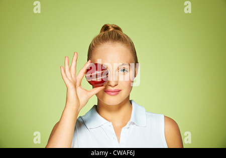 Giovane donna holding cricket palla oltre il suo occhio Foto Stock