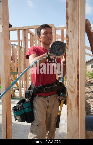 I dipendenti della società, maschio asiatici danno volontariamente il loro tempo, contribuire a costruire una casa a prezzi accessibili con Habitat for Humanity in Austin, Texas. Foto Stock